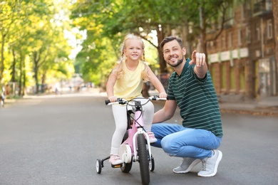 Photo of Father teaching daughter to ride bicycle on street