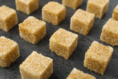 Photo of Brown sugar cubes on grey table, closeup