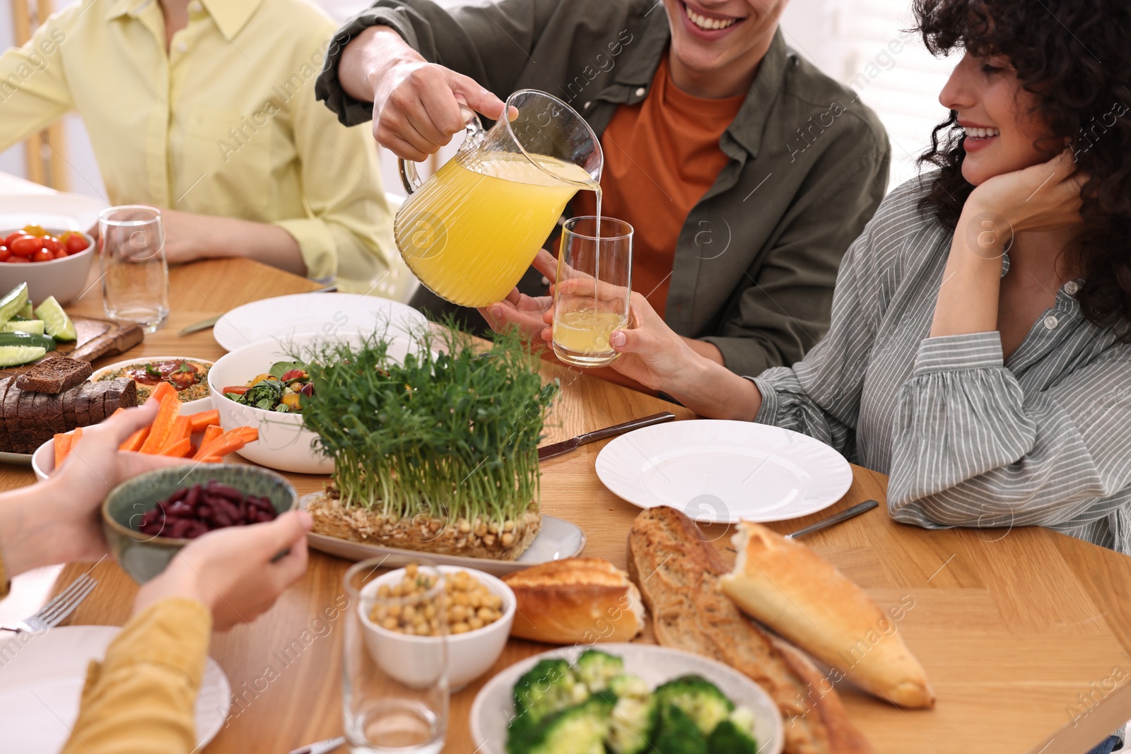 Photo of Friends eating vegetarian food at wooden table indoors