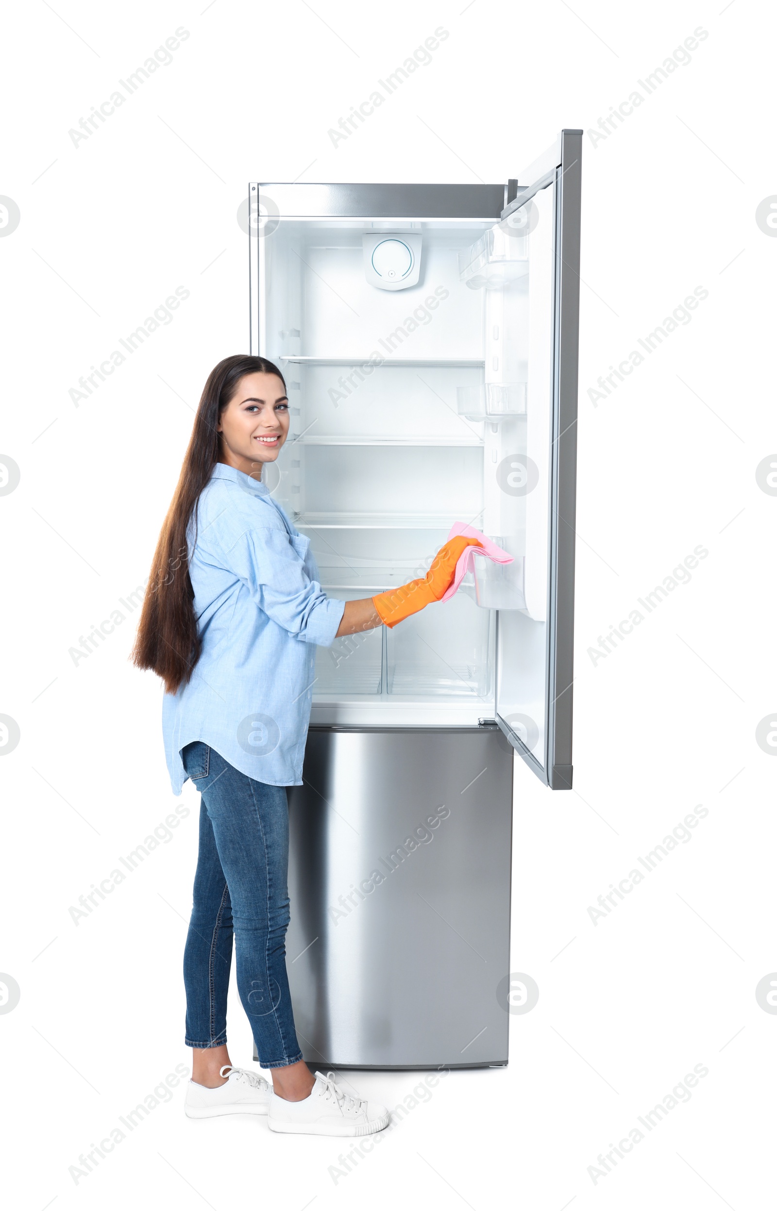 Photo of Young woman cleaning refrigerator with rag on white background