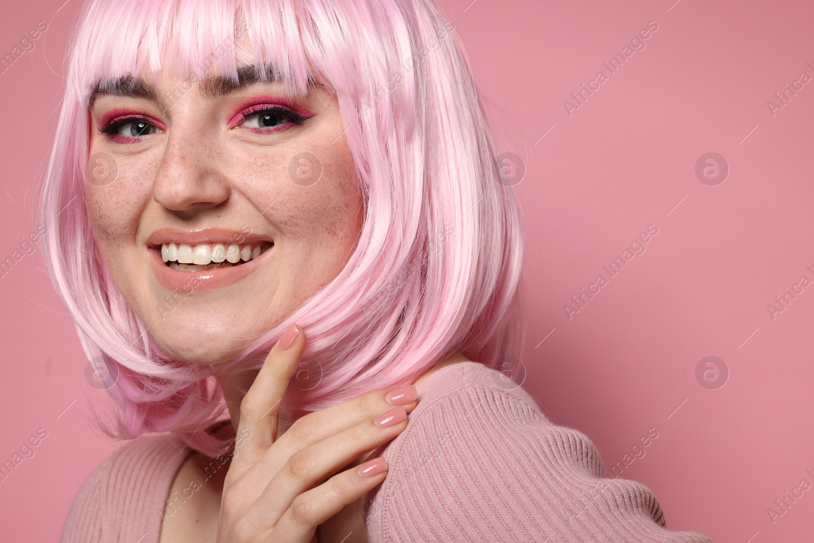 Photo of Happy woman with bright makeup and fake freckles on pink background, closeup