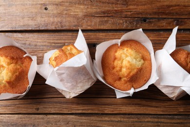 Delicious sweet muffins on wooden table, flat lay