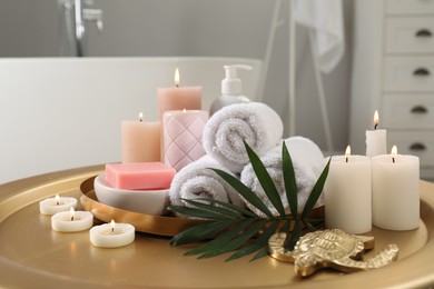 Composition with different spa products, burning candles and palm leaf on table in bathroom