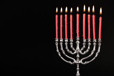 Silver menorah with burning candles on black background, space for text. Hanukkah celebration