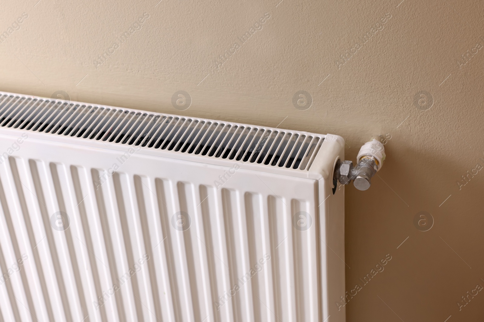 Photo of Modern radiator on beige wall. Central heating system