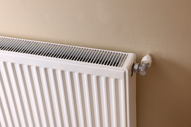 Photo of Modern radiator on beige wall. Central heating system