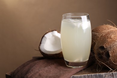 Photo of Glass of coconut water and nuts on wooden table, space for text