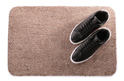 Stylish door mat with shoes on white background, top view