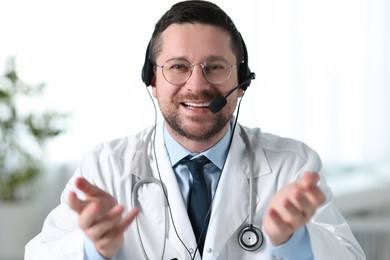 Photo of Smiling doctor in headset having online consultation in clinic