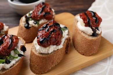 Photo of Delicious bruschettas with sun-dried tomatoes, cream cheese and balsamic vinegar on table, closeup