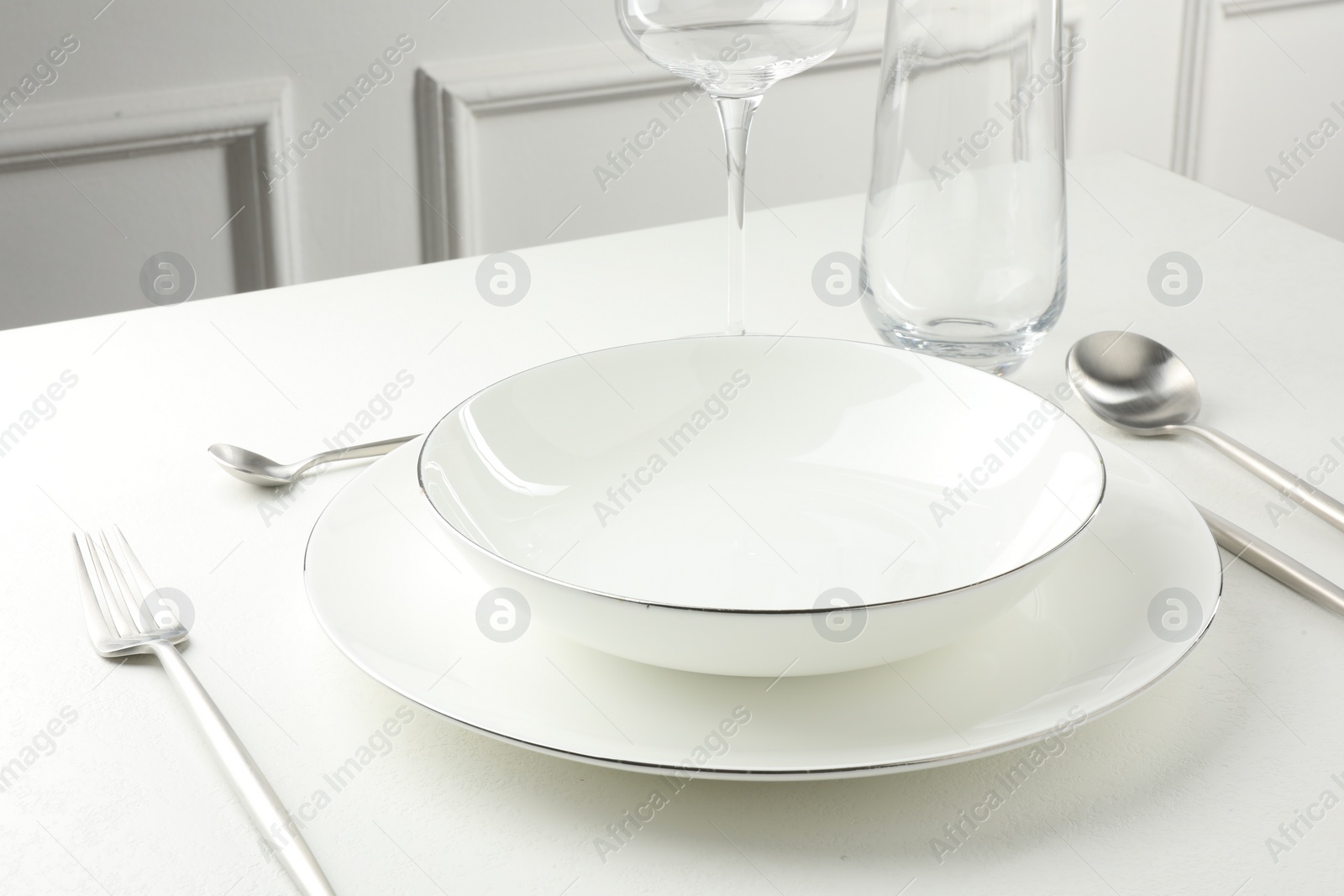 Photo of Stylish setting with cutlery and glasses on white textured table
