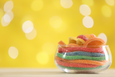 Photo of Delicious colorful candies on light table against blurred lights. Space for text