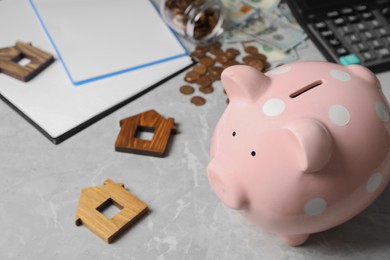 Photo of Piggy bank and wooden house models on grey marble table