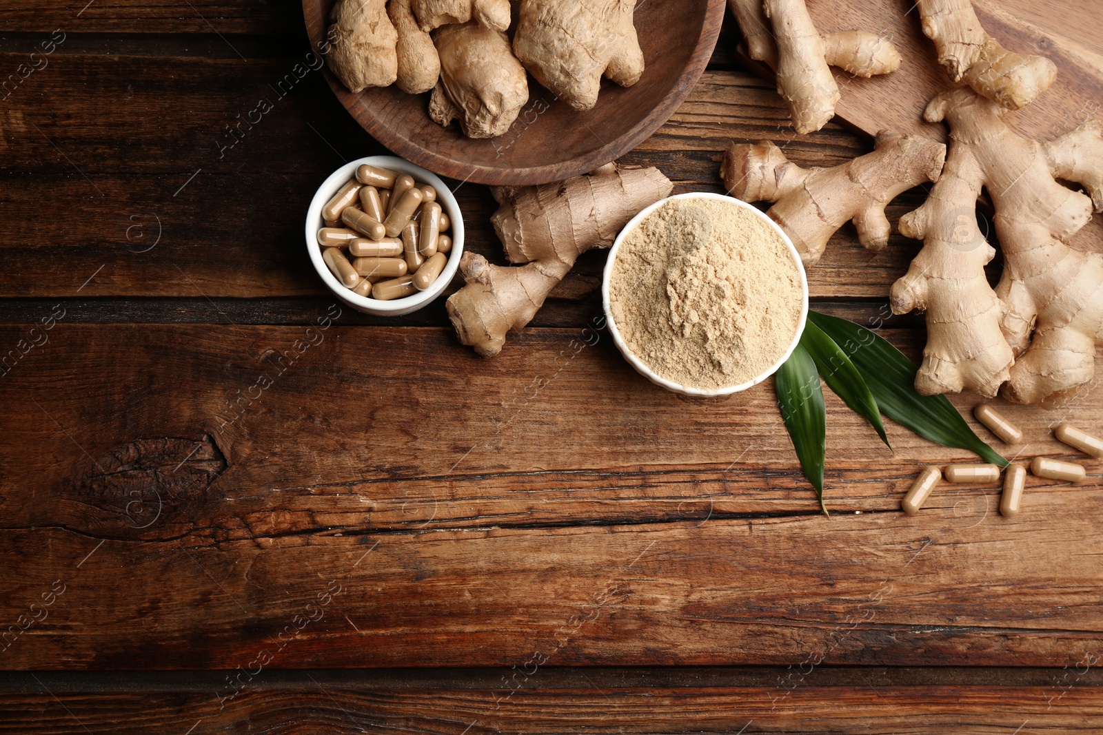 Photo of Dry, fresh and capsuled ginger on wooden table, flat lay. Space for text