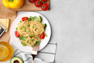 Photo of Plate of delicious pasta primavera and ingredients on light gray table, flat lay. Space for text