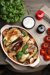 Photo of Delicious eggplant lasagna in baking dish on wooden table, flat lay