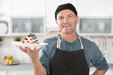 Professional male chef with plate of delicious dessert in kitchen