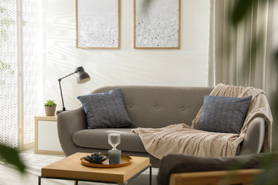 Modern living room interior with comfortable sofa near light wall