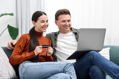 Photo of Happy couple with laptop and credit card shopping online together at home