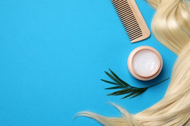 Photo of Lockhealthy blond hair, cosmetic product and comb on light blue background, flat lay. Space for text