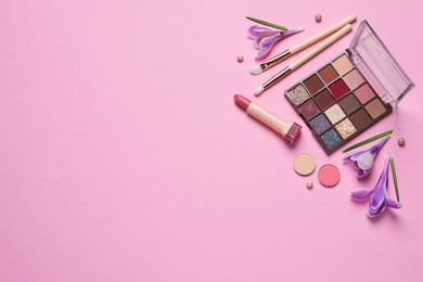 Flat lay composition with different makeup products and beautiful flowers on pink background. Space for text