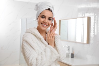 Photo of Happy young woman with towel on head in bathroom, space for text. Washing hair
