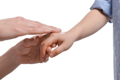 Mother applying ointment on her daughter's hand against white background, closeup