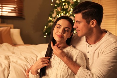 Photo of Happy couple in festively decorated bedroom. Christmas celebration