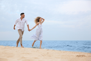 Happy couple running on beach, space for text. Romantic walk