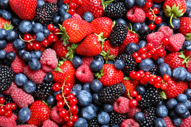 Photo of Mix of different ripe tasty berries as background, top view