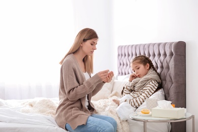 Photo of Mother taking care of little daughter suffering from cold in bed