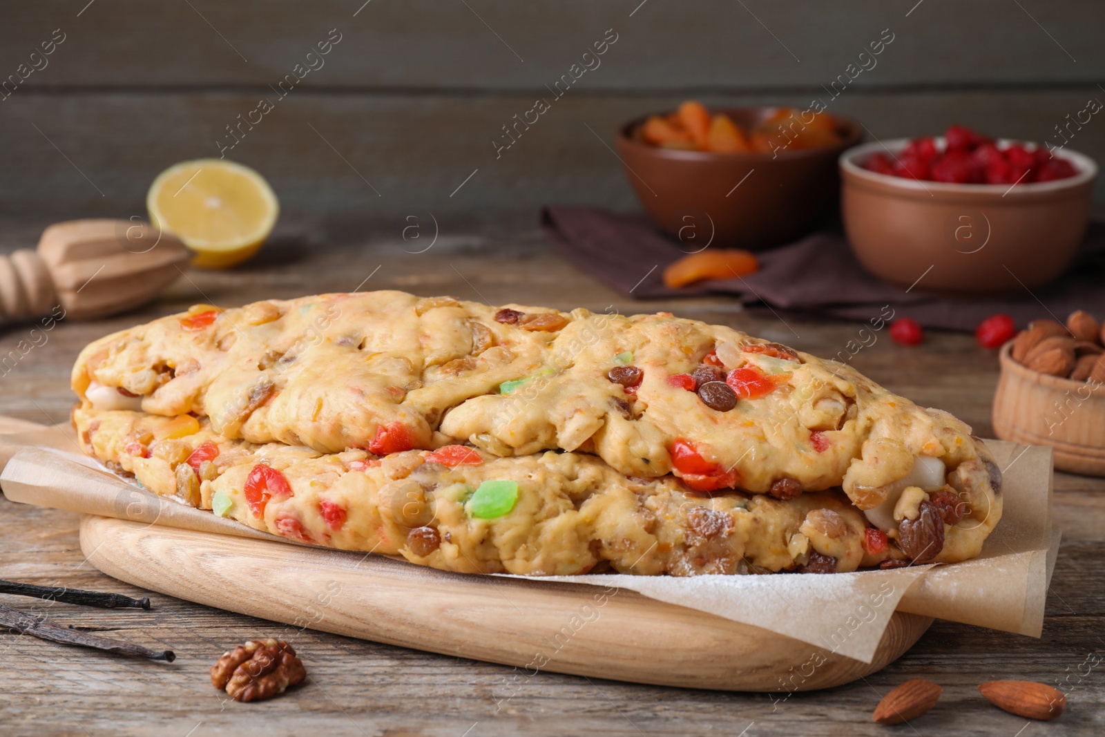 Photo of Unbaked Stollen with candied fruits and raisins on wooden table, closeup