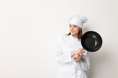 Photo of Professional chef with frying pan on light background. Space for text