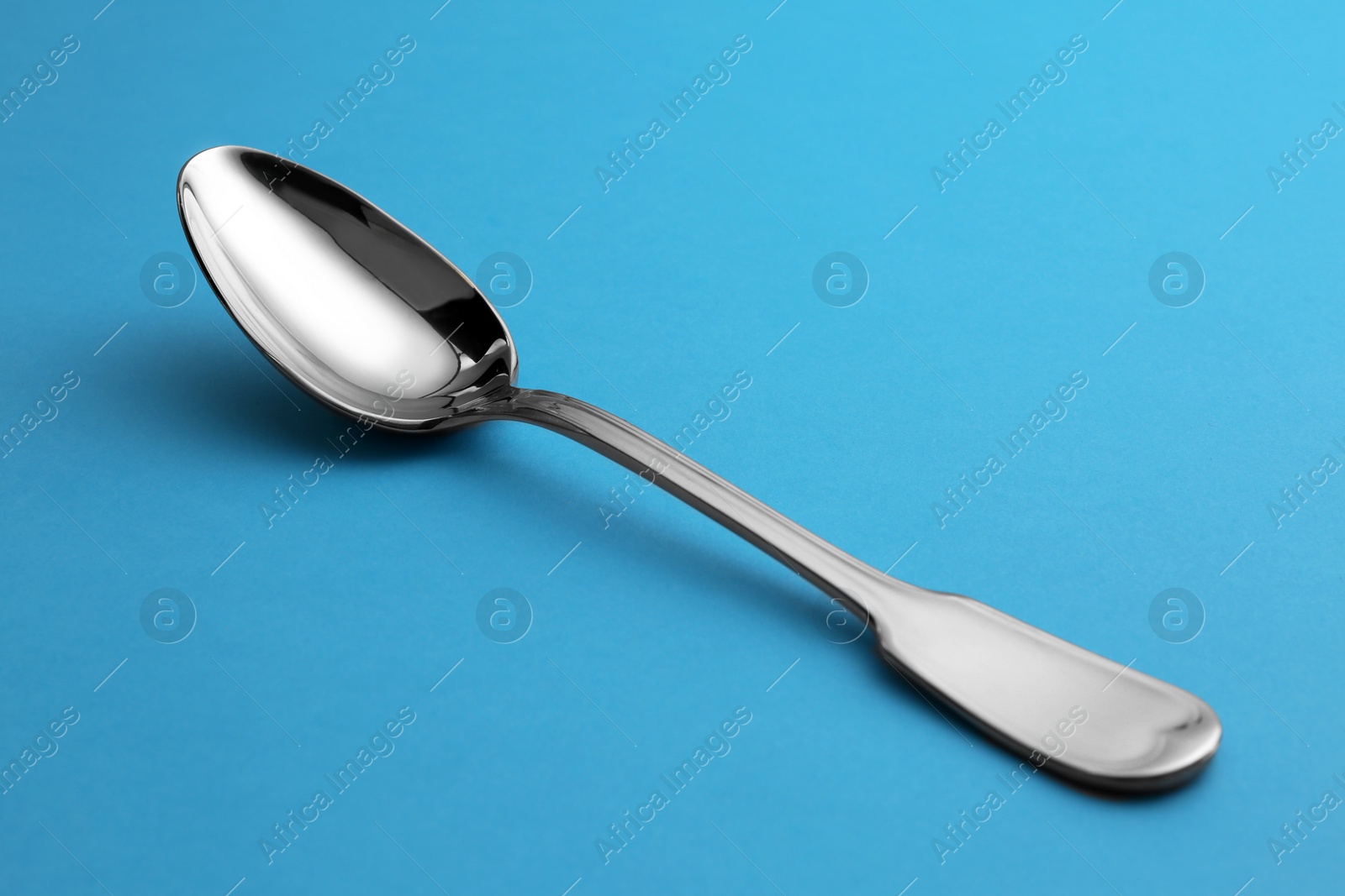 Photo of Clean empty tea spoon on blue background