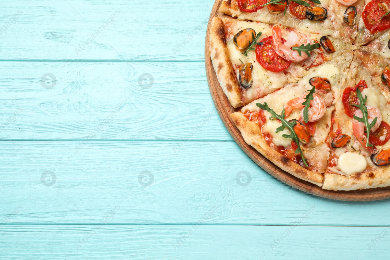 Photo of Delicious seafood pizza on light blue wooden table, top view. Space for text