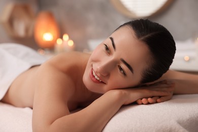 Photo of Beautiful woman relaxing on massage couch in spa salon