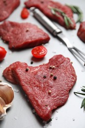 Fresh raw meat steaks and spices on light grey table, closeup