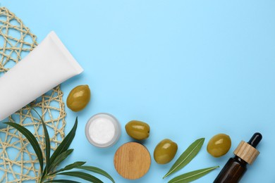 Photo of Cosmetic products with olive essential oil light turquoise background, flat lay. Space for text
