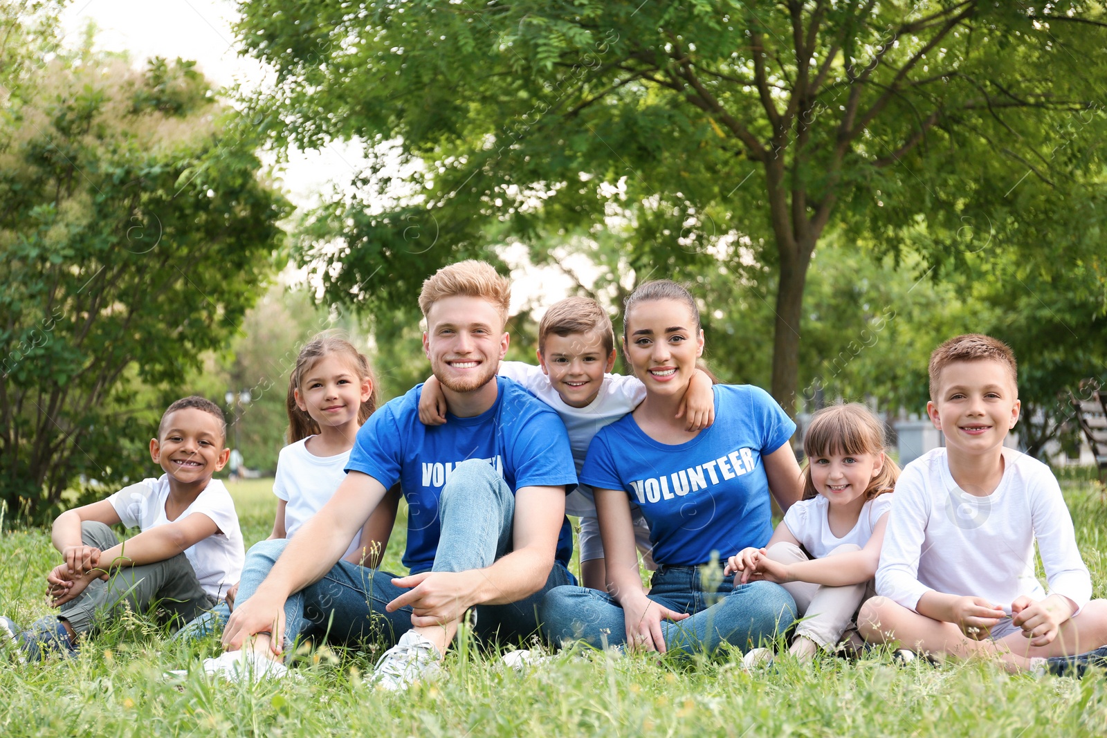 Photo of Volunteers and kids sitting on grass in park