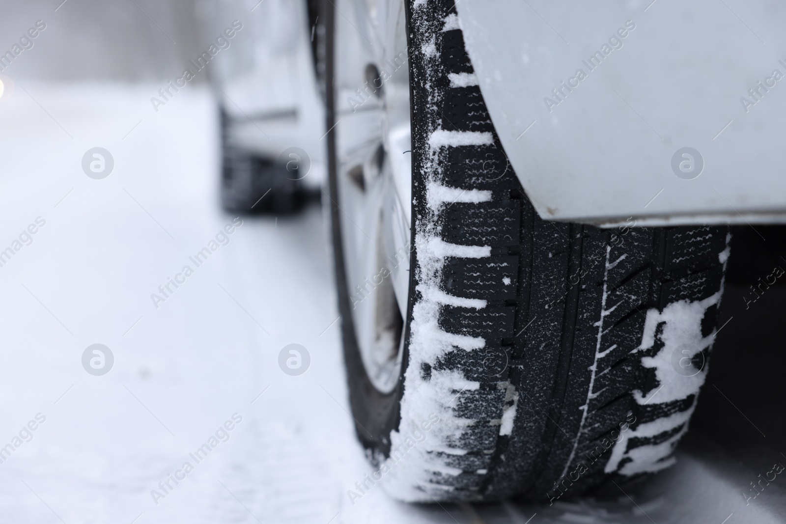 Photo of Car with winter tires on snowy road outdoors, closeup. Space for text