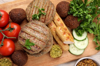 Different tasty vegan meat products and fresh vegetables on wooden table, flat lay