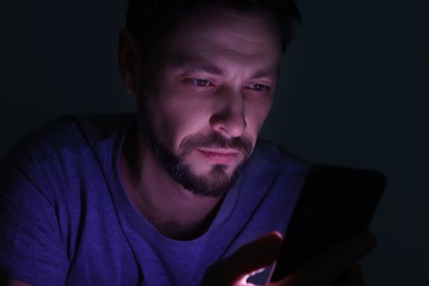 Photo of Man using smartphone at night. Internet addiction