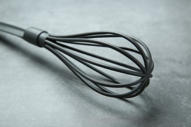 Photo of Plastic whisk on gray table, closeup. Kitchen tool