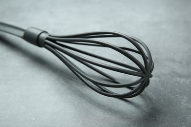 Plastic whisk on gray table, closeup. Kitchen tool