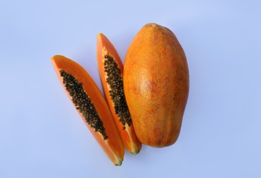 Photo of Fresh juicy cut and whole papaya fruits on white background, flat lay