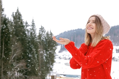 Photo of Happy young woman in warm clothes outdoors, space for text. Winter vacation