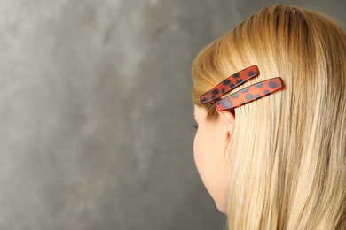 Young woman with beautiful hair clips on grey background, space for text