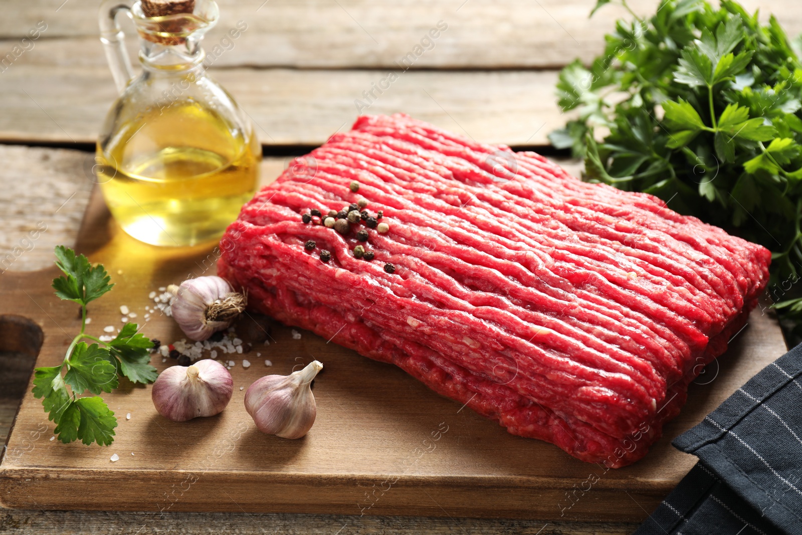 Photo of Raw ground meat, spices, parsley and oil on wooden table