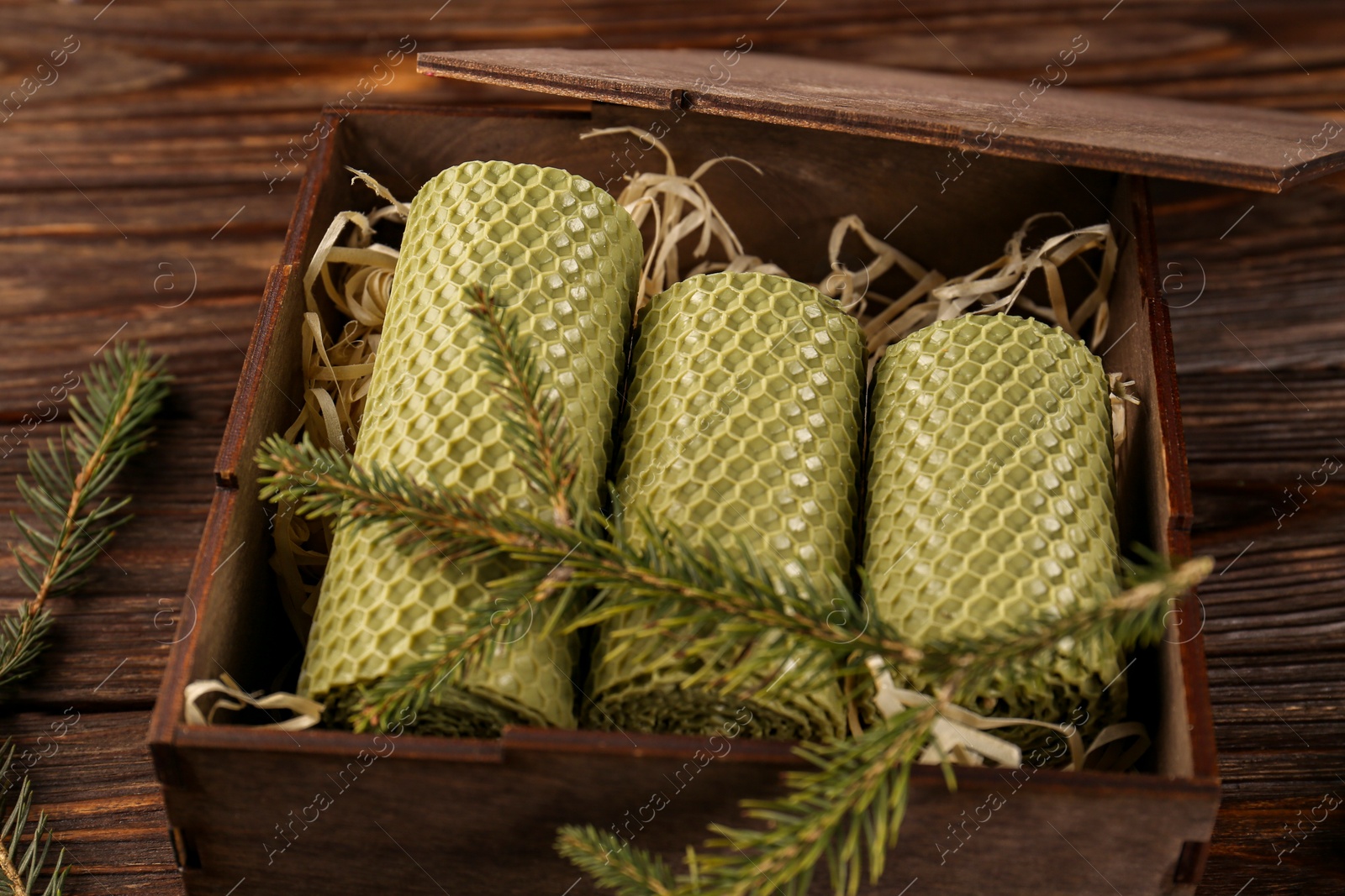 Photo of Stylish elegant beeswax candles with spruce branch on wooden table