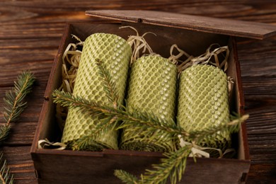 Stylish elegant beeswax candles with spruce branch on wooden table